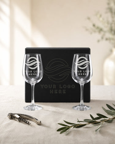 Two custom logo stemmed wine glasses beside a black magnetic box with outline artwork on the lid.