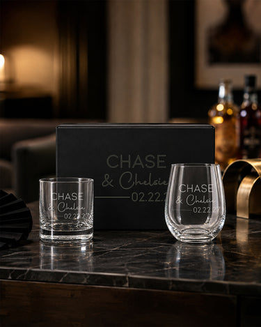 Whiskey and Stemless Wine Glass Set with two names in print and script, a divider and date beside a matching engraved black magnetic gift box.