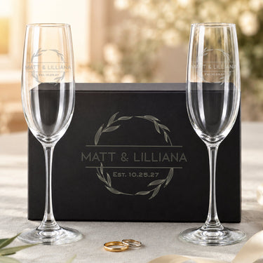 Personalized champagne glasses with the N8 names and date design beside a black magnetic gift box.
