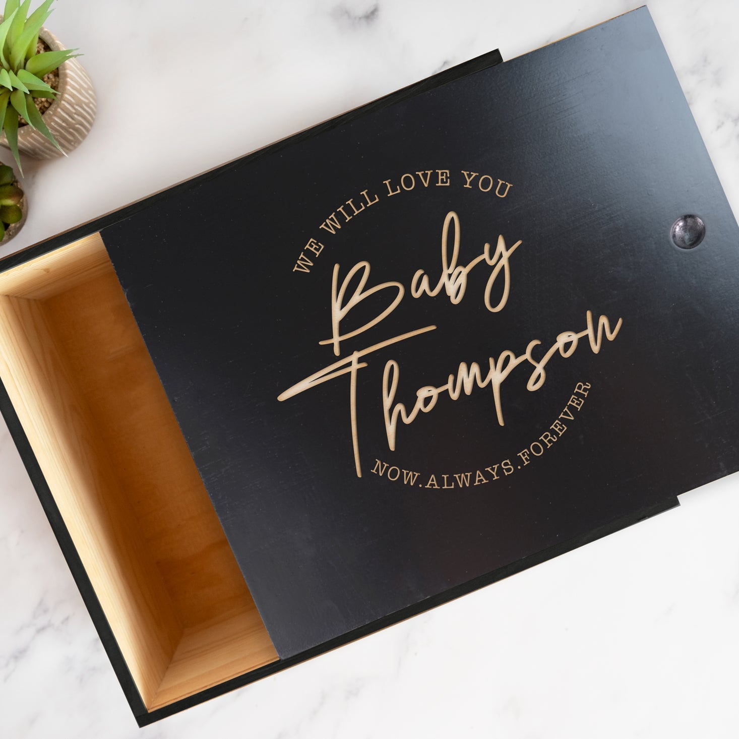 Black gift box with custom engraved text on a marble surface