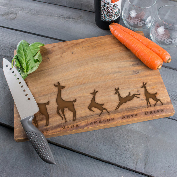 Engraved wood block cutting board. The engraving is on the front and towards the lower bottom part of the board. The engraving is of a family of deer lined in a row. There is a dad deer, mom deer and three kids. Under each deer has a printed name "Dad, Mama, Jameson, Anya, Brian". Deer can be added or taken away.