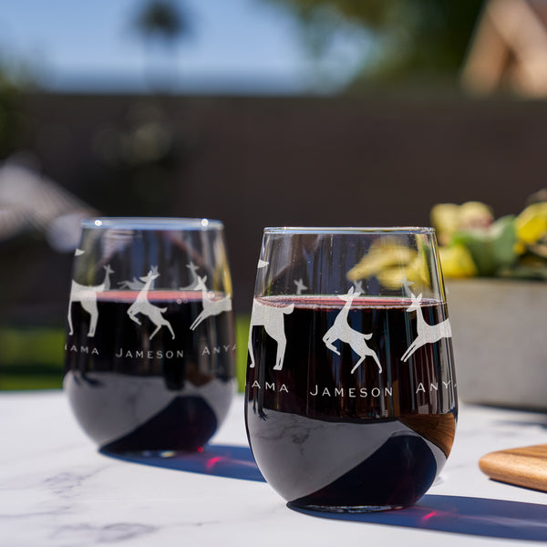Etched stemless red wine glass. The etching wraps around the glass. The design is of a family of deer lined in a row. There is a dad deer, mom deer and three kids. Under each deer has a printed name "Dad, Mama, Jameson, Anya, Brian". Deer can be added or taken away.