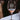 Stemmed wine glass on a table. The glass has an etched design centered. The design is of a square with swirly horizontal lines, and in the middle is the letter "D" in caps. Below the square is the name "DANIELS" in all caps. 
